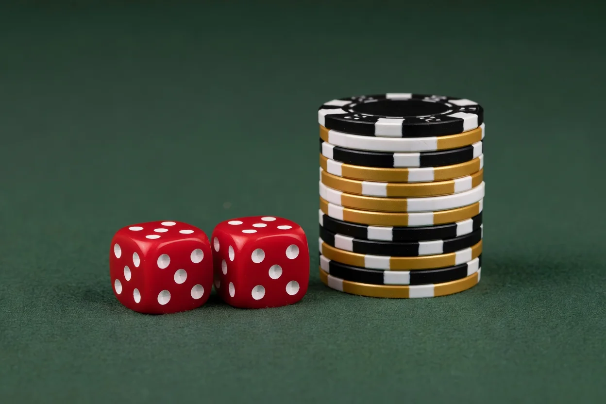 Pair of red dice and stacked casino chips on plain dark green felt